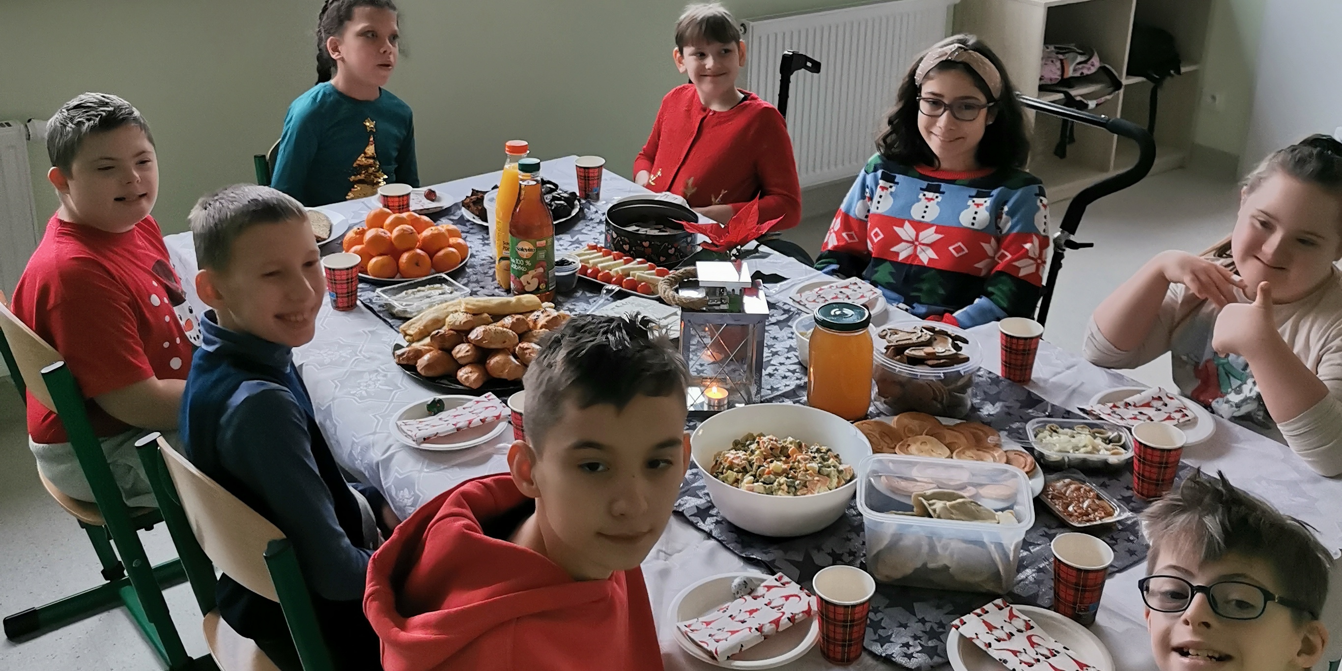 Uczniowie siedzą wokół wigilijnego stołu.