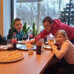 Uczniowie jedzą pizzę w pizzerni.