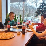 Uczniowie jedzą pizzę w pizzerni.