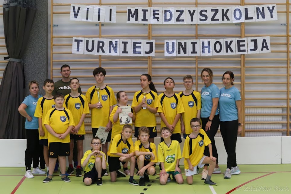 Uczniowie w strojach sportowych i nauczyciela.
