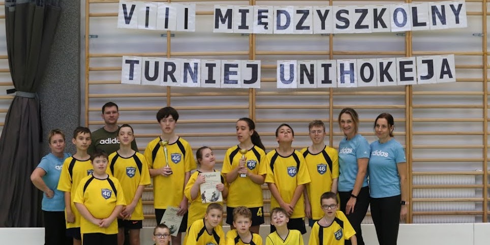 Uczniowie w strojach sportowych i nauczyciela.