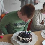 Jubilat zdmuchuje świeczki na torcie.