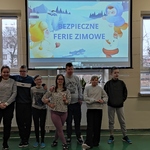 Grupa uczniów na tle ekranu z napisem Bezpieczne ferie zimowe.