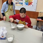 Uczeń przelewa łyżką jogurt do salaterki