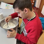 Uczeń miesza łyżką mąkę i cukier w misce