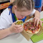Uczennica dekoruje pizzę
