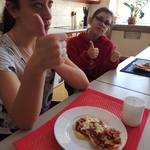 Uczennice siedzą przy stole. Przed nimi stoją talerze z pizzerinkami