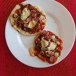 Na czerwonej podkładce stoi talerz z dwiema pizzerinkami