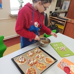 Uczennica dekoruje pizzerinki leżące na blaszce