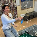 Nauczyciel trzyma lejek i  balon, wokół unoszą się srebrne papierki imitujące płatki śniegu
