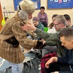 Nauczyciel ubrany futro i czapkę wita się z uczniami