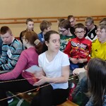 Uczniowie siedzący na ławeczkach w trakcie spotkania