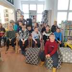 Uczniowie siedzą na krzesłach w bibliotece.