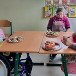 Uczennice siedzą przy stole, przed nimi leżą kanapki.