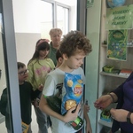 Uczeń stoi w otwartych drzwiach do klasy. Za nim stoją koledzy z klasy.