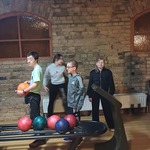 Grupa uczniów stoi na torze do gry w kręgle. Jedna osoba trzyma kulę do kręgli.