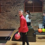 Uczeń z kulą w ręku stoi na torze do gry w kręgle.