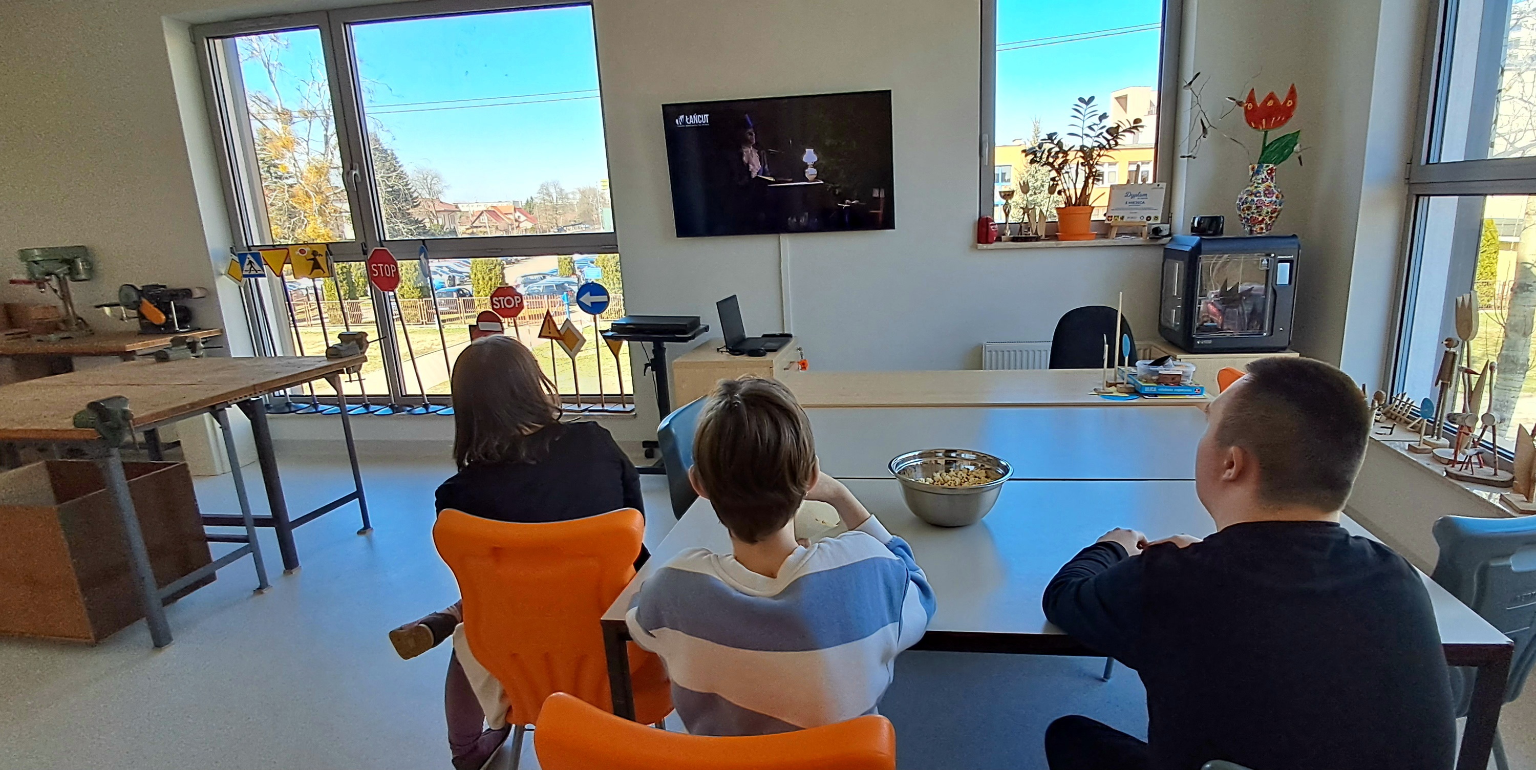Uczniowie oglądają program w telewizji.