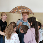 Nauczycielka  trzyma parasolkę. Obok stoją uczniowie.