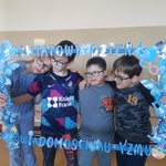 Czwórka uczniów trzyma niebieską ramkę z napisem  - Światowy Dzień Świadomości Autyzmu.