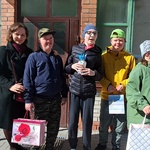 Nauczycielka i czwórka uczniów stoją przed wejściem do bloku.