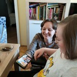 Nauczycielka pokazuje uczennicy zdjęcie wyświetlane na ekranie telefonu.