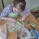Uczennica siedzi przy stoliku i kroi ogórek.