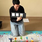 Nauczyciel wskazuje palcem na symbole tworzące zdanie. Przed nim w foremkach kurczaki z pianki do golenia