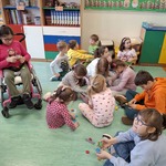 Grupa uczniów siedzi na dywanie
