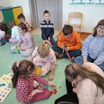 Grupa uczniów siedzi na podłodze i układa klocki