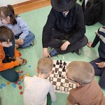 Uczniowie siedzą na podłodze i grają w szachy