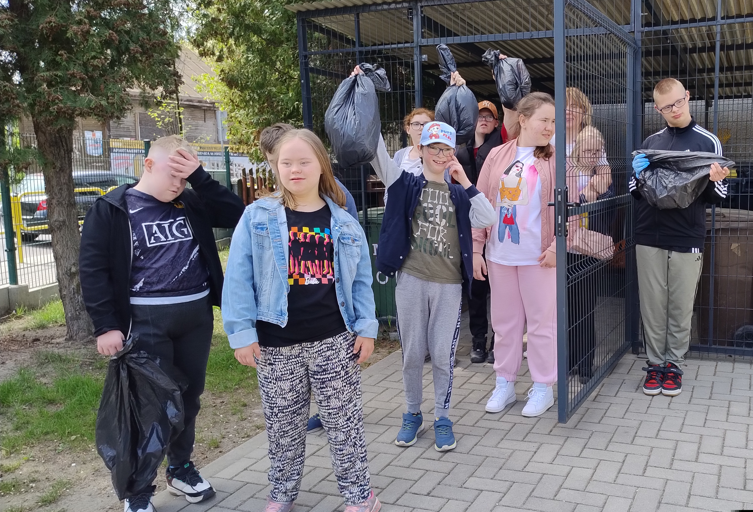 Grupa uczniów z zebranymi do worków śmieciami.