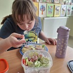 Uczennica je przygotowaną przez siebie sałatkę