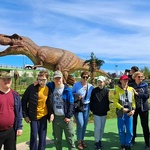 Nauczycielki i uczniowie na tle makiety dinozaura
