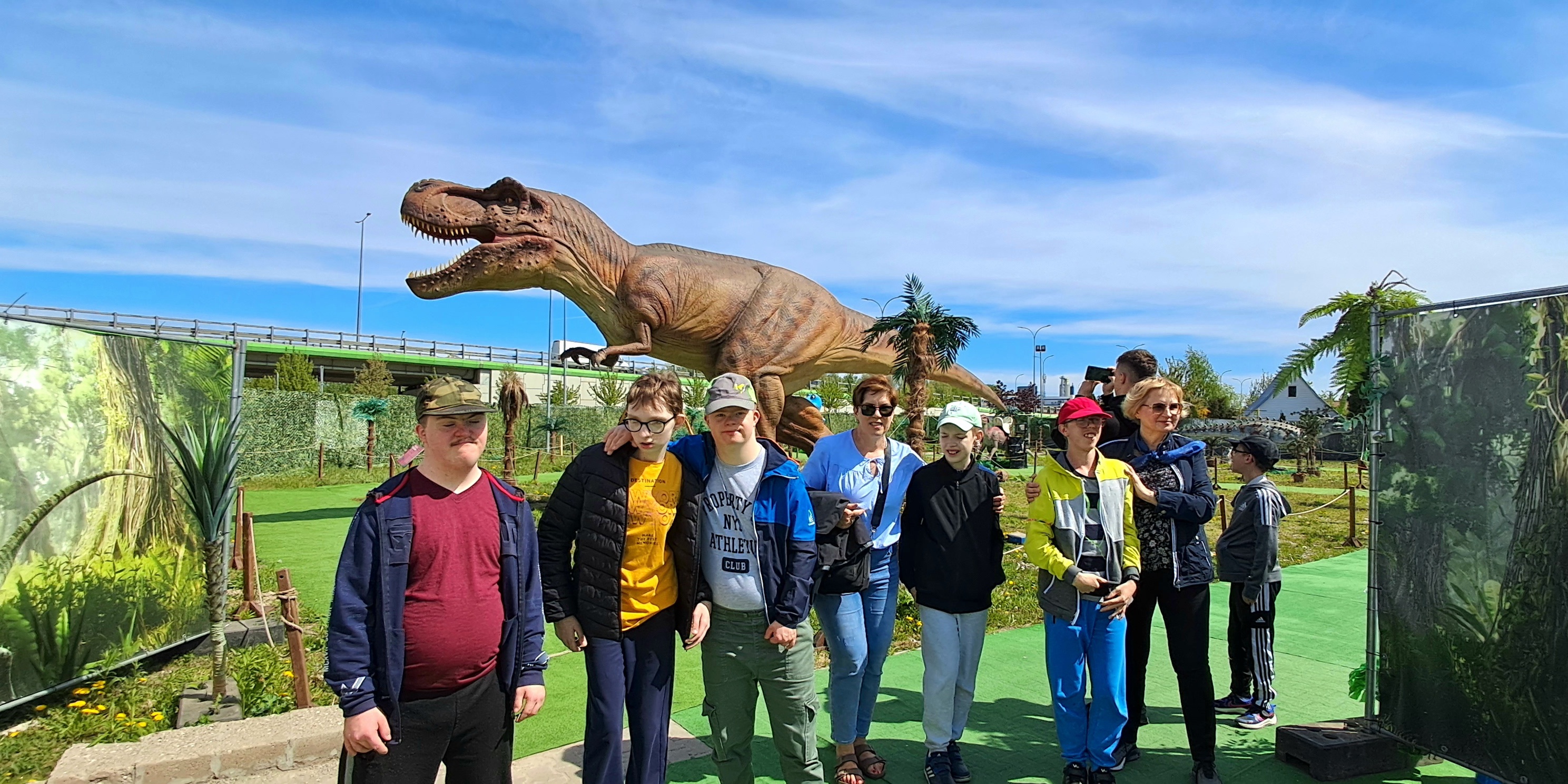 Nauczycielki i uczniowie na tle makiety dinozaura