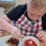 Uczeń podczas krojenia truskawek.