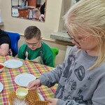 Uczniowie siedzą przy stole, prezentują swoje gofry.