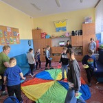 Grupa uczniów i nauczycielka chodzą wokół chusty animacyjnej