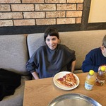 Uczennica siedzi przy stole. Przed nią stoi talerz z pizzą