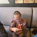 Uczennica siedzi przy stole i je pizzę