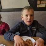 Uczeń siedzi przy stole i je pizzę