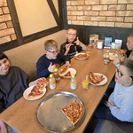 Uczniowie siedzą przy stole i jedzą pizzę