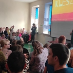 Nauczycielka omawia slajd wyświetlany na ekranie. Na ławkach siedzą uczniowie