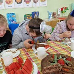 Uczniowie siedzą za urodzinowym stołem i jedzą tort