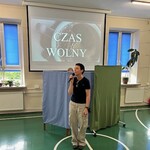 Nauczyciel z mikrofonem wita uczniów