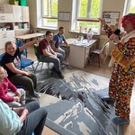 Klaun trzyma szczotkę i śpiewa, dzieci uśmiechają się