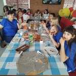 Grupa osób siedzi przy stole i je pizzę