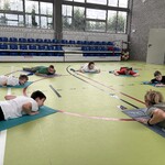 Szkolna sala gimnastyczna. Uczniowie wykonują ćwiczenia na matach