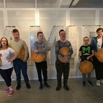 Dwie nauczycielki i grupa uczniów na tle liter PAMIĘĆ