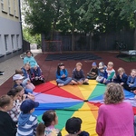 Grupa uczniów siedzi w dużym kole na  chuście animacyjnej